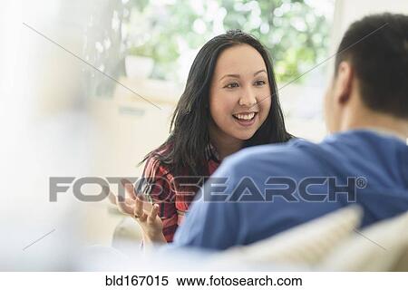 Couple talking on sofa in living room View Large Photo Image Stock Photography - Couple talking on sofa in living room. Fotosearch