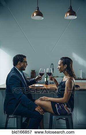 Stock Photo - Couple toasting with wine at counter. Fotosearch
