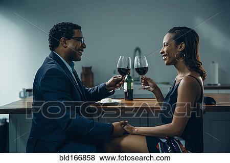 Stock Photo - Couple toasting with wine at counter. Fotosearch