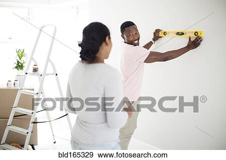 Couple using level in new home View Large Photo Image Stock Photo - Couple using level in new home. Fotosearch