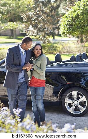 Stock Photo - Couple walking in driveway at convertible. Fotosearch
