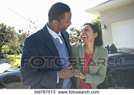 Stock Image - Couple walking near convertible. Fotosearch
