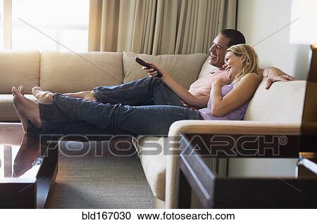 Couple watching television on sofa View Large Photo Image Stock Image - Couple watching television on sofa. Fotosearch