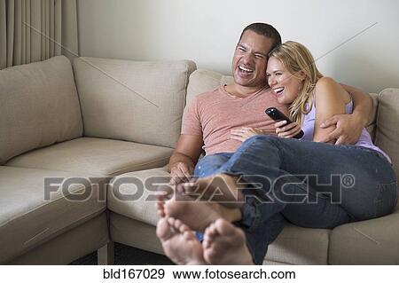 Stock Photo - Couple watching television on sofa. Fotosearch