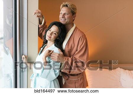Stock Photo - Couple wearing bathrobes at bedroom window. Fotosearch