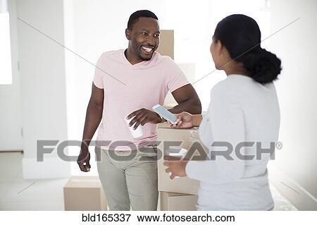 Couple with cardboard boxes in new home View Large Photo Image Stock Photo - Couple with cardboard boxes in new home. Fotosearch