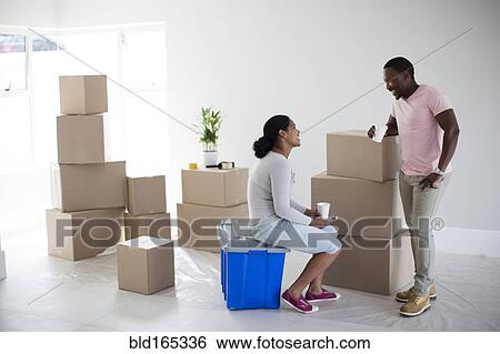 Stock Photograph - Couple with cardboard boxes in new home. Fotosearch