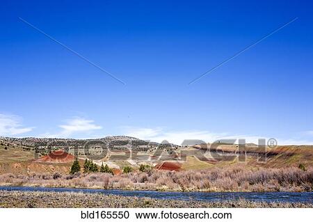 Stock Image - Creek near hills in desert landscape under blue sky, Painted Hills, Oregon, United States. Fotosearch