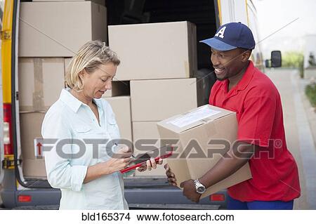 Delivery man holding cardboard box with customer View Large Photo Image Picture - Delivery man holding cardboard box with customer . Fotosearch