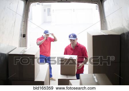 Stock Photo - Delivery men unloading packages in van. Fotosearch
