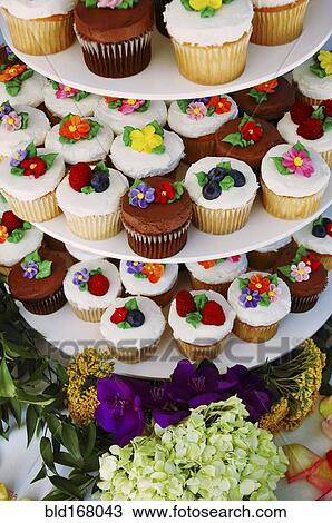 Stock Image - Display stand with decorated floral cupcakes. Fotosearch