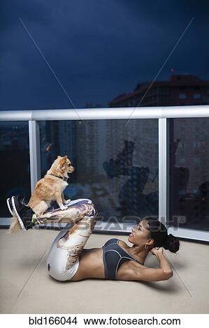 Picture - Dog balancing on legs of mixed race athlete during exercise. Fotosearch
