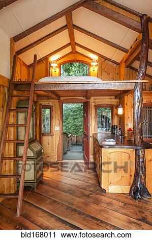 Stock Image - Doorway and loft bedroom in wooden tree house. Fotosearch