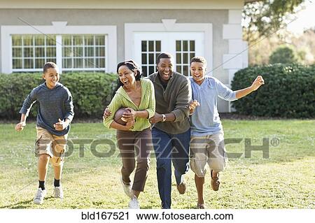 Stock Image - Family playing football in backyard. Fotosearch