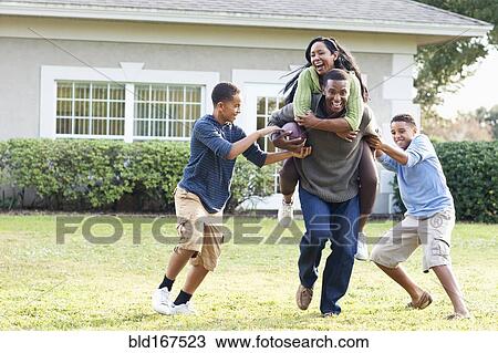 Family playing football in backyard View Large Photo Image Stock Image - Family playing football in backyard. Fotosearch