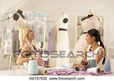 Stock Image - Fashion designers talking in studio. Fotosearch