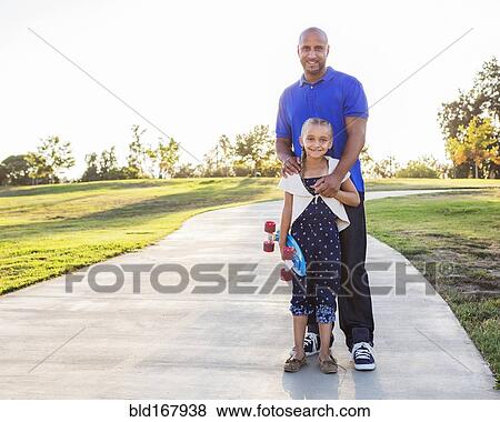 Father and daughter hugging with skateboard in park View Large Photo Image Stock Photo - Father and daughter hugging with skateboard in park. Fotosearch