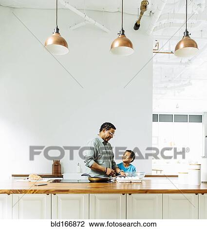 Stock Image - Father and son cooking in kitchen. Fotosearch