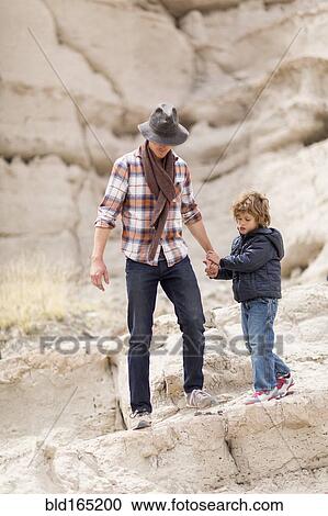 Stock Image - Father and son exploring desert rock formations. Fotosearch