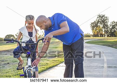 Father teaching daughter to ride bicycle in park View Large Photo Image Stock Image - Father teaching daughter to ride bicycle in park. Fotosearch