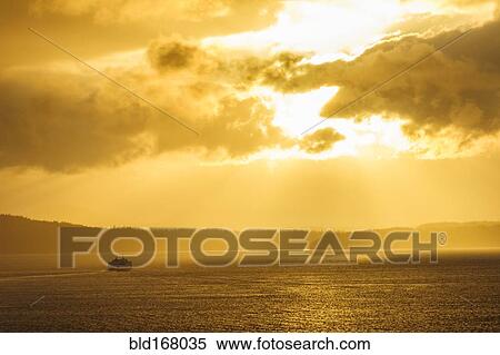 Stock Photography - Ferry on ocean water under dramatic sky. Fotosearch