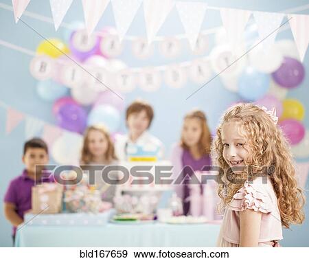 Stock Photo - Girl smiling at birthday party. Fotosearch
