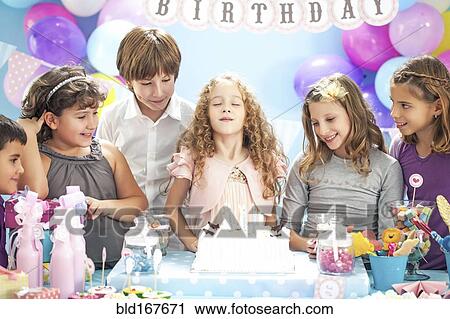Girl wishing over birthday cake at party View Large Photo Image Stock Image - Girl wishing over birthday cake at party. Fotosearch