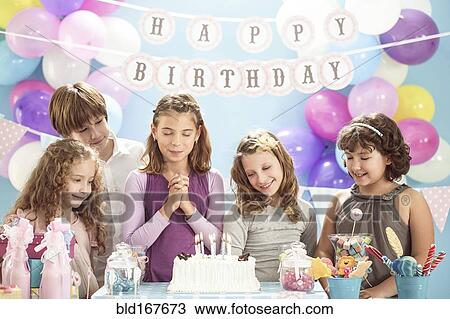Girl wishing over birthday cake at party View Large Photo Image Stock Image - Girl wishing over birthday cake at party. Fotosearch