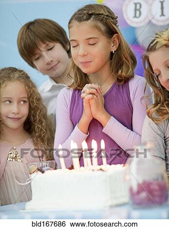 Girl wishing over birthday cake at party View Large Photo Image Stock Photograph - Girl wishing over birthday cake at party. Fotosearch