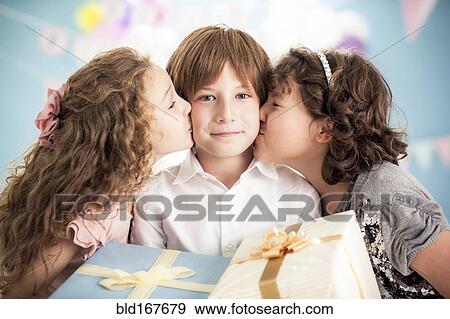 Stock Photo - Girls kissing cheeks of boy at birthday party. Fotosearch