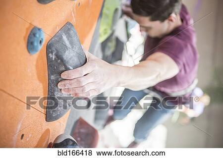 Stock Photo - High angle view of athlete climbing rock wall in gym. Fotosearch