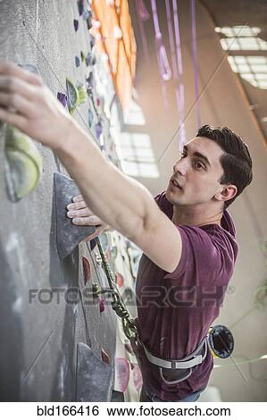 Stock Photograph - High angle view of athlete climbing rock wall in gym. Fotosearch