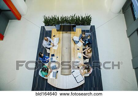 Stock Image - High angle view of business people working in office meeting. Fotosearch