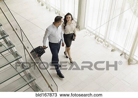 Stock Image - High angle view of business people rolling luggage in hotel lobby. Fotosearch