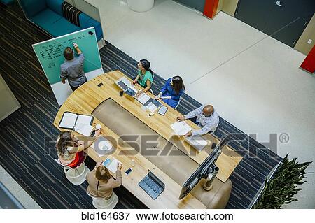 Stock Photo - High angle view of business people working in office meeting. Fotosearch