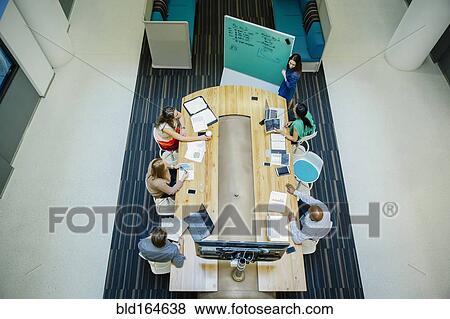 Stock Photo - High angle view of business people working in office meeting. Fotosearch