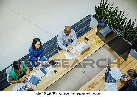 Stock Photo - High angle view of business people working in office meeting. Fotosearch