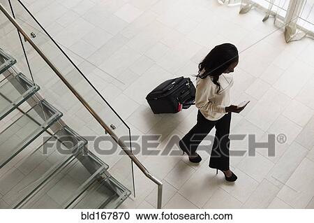 High angle view of businesswoman rolling luggage in hotel lobby View Large Photo Image Stock Image - High angle view of businesswoman rolling luggage in hotel lobby. Fotosearch