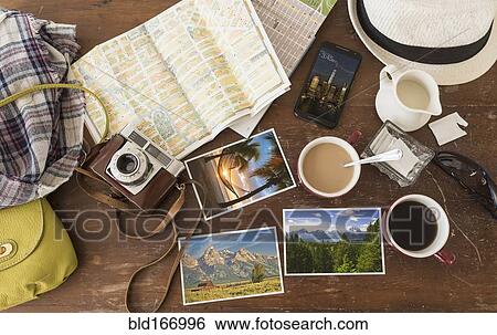 Stock Photograph - High angle view of coffee, maps, photographs, camera and cell phone. Fotosearch