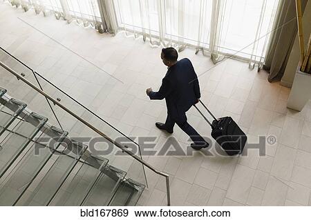 High angle view of Hispanic businessman rolling luggage in hotel lobby View Large Photo Image Stock Photo - High angle view of Hispanic businessman rolling luggage in hotel lobby. Fotosearch