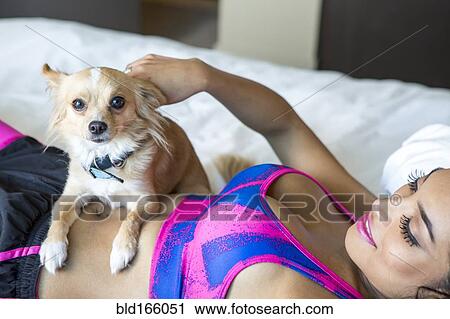 Hispanic athlete petting dog on bed View Large Photo Image Stock Image - Hispanic athlete petting dog on bed. Fotosearch