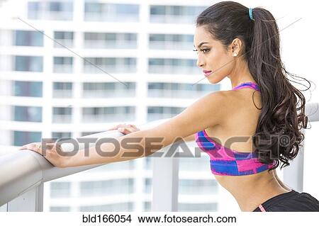 Picture - Hispanic athlete stretching on balcony. Fotosearch