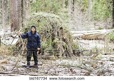 Hispanic boy building hut from branches in forest View Large Photo Image Picture - Hispanic boy building hut from branches in forest. Fotosearch
