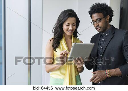Stock Photograph - Hispanic business people using digital tablet in office. Fotosearch