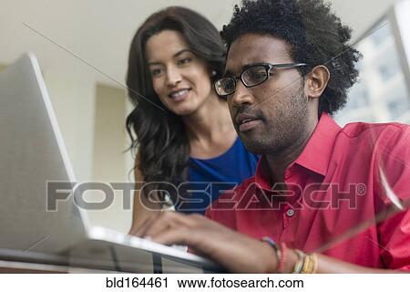Hispanic business people using laptop at glass office desk View Large Photo Image Stock Image - Hispanic business people using laptop at glass office desk. Fotosearch