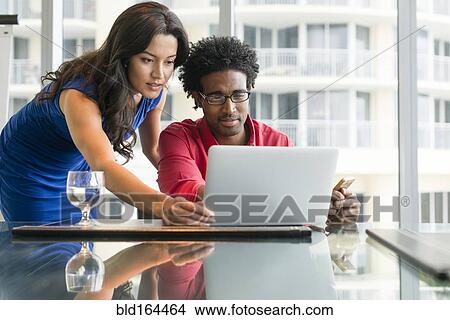 Picture - Hispanic business people working at office desk. Fotosearch
