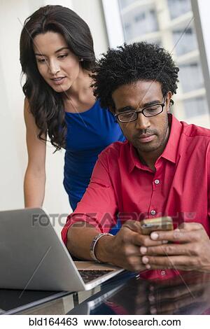 Stock Image - Hispanic business people working at office desk. Fotosearch