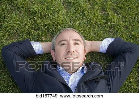 Stock Photo - Hispanic businessman laying on grass. Fotosearch