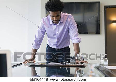 Stock Photo - Hispanic businessman leaning over conference table. Fotosearch