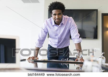 Stock Photo - Hispanic businessman leaning over conference table. Fotosearch